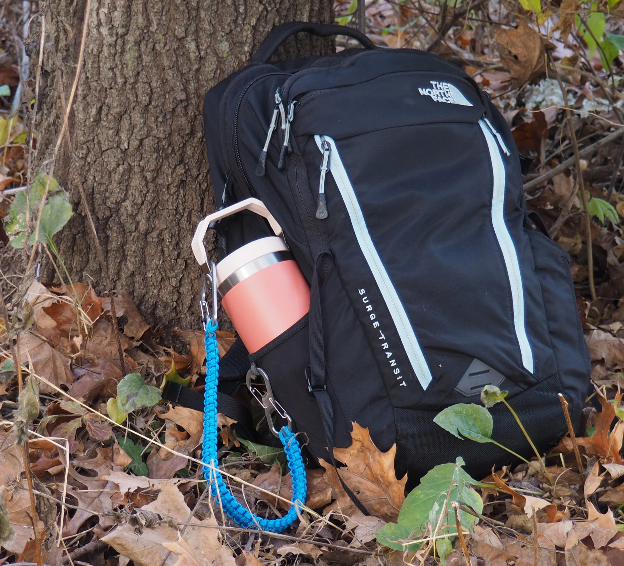 Blue THIRSTLOCK™ HITCH™ bottle leash securing a Stanley water bottle to a backpack.