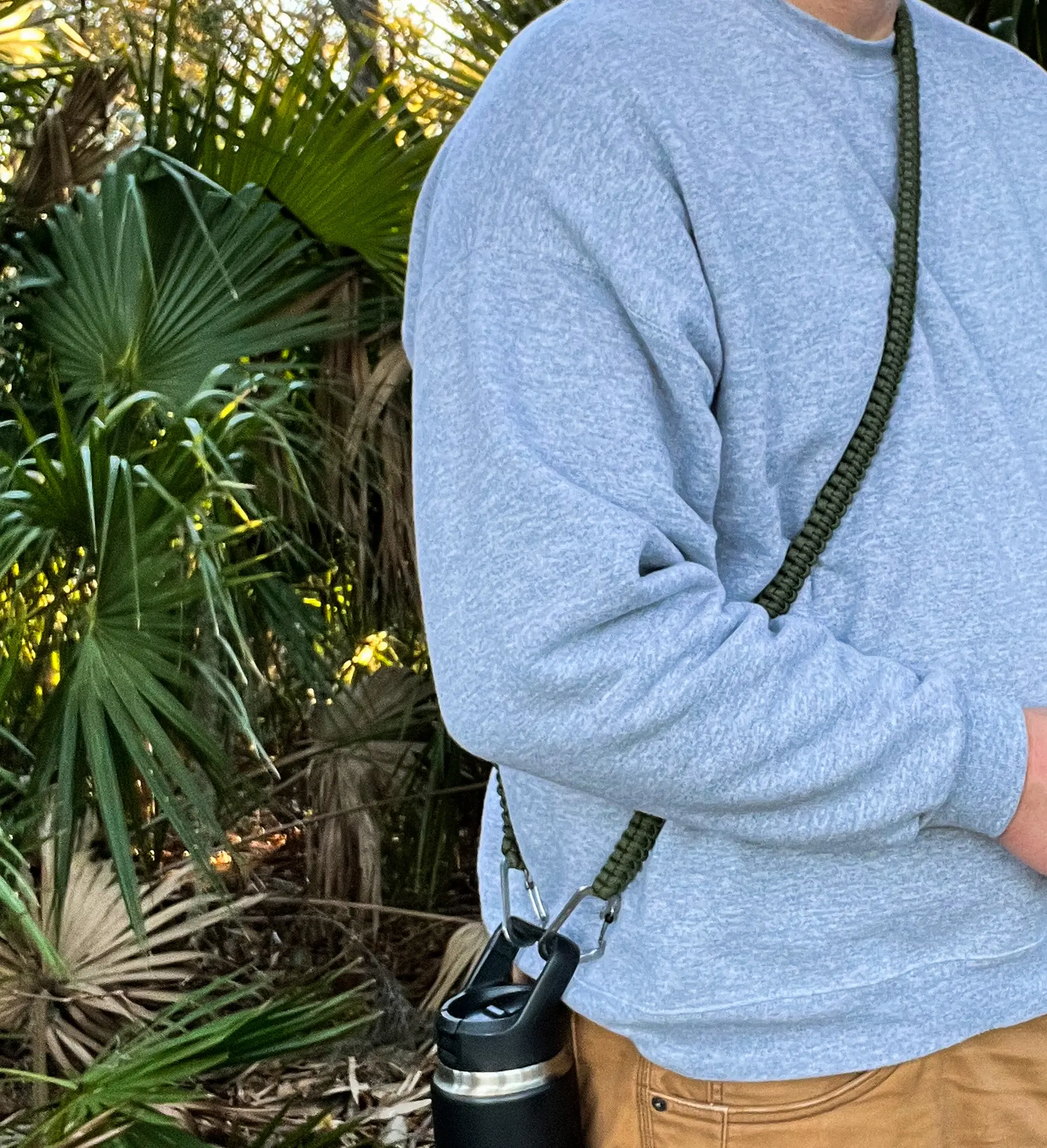 Olive THIRSTLOCK™ SOLO™ bottle sling worn cross-body on the torso.