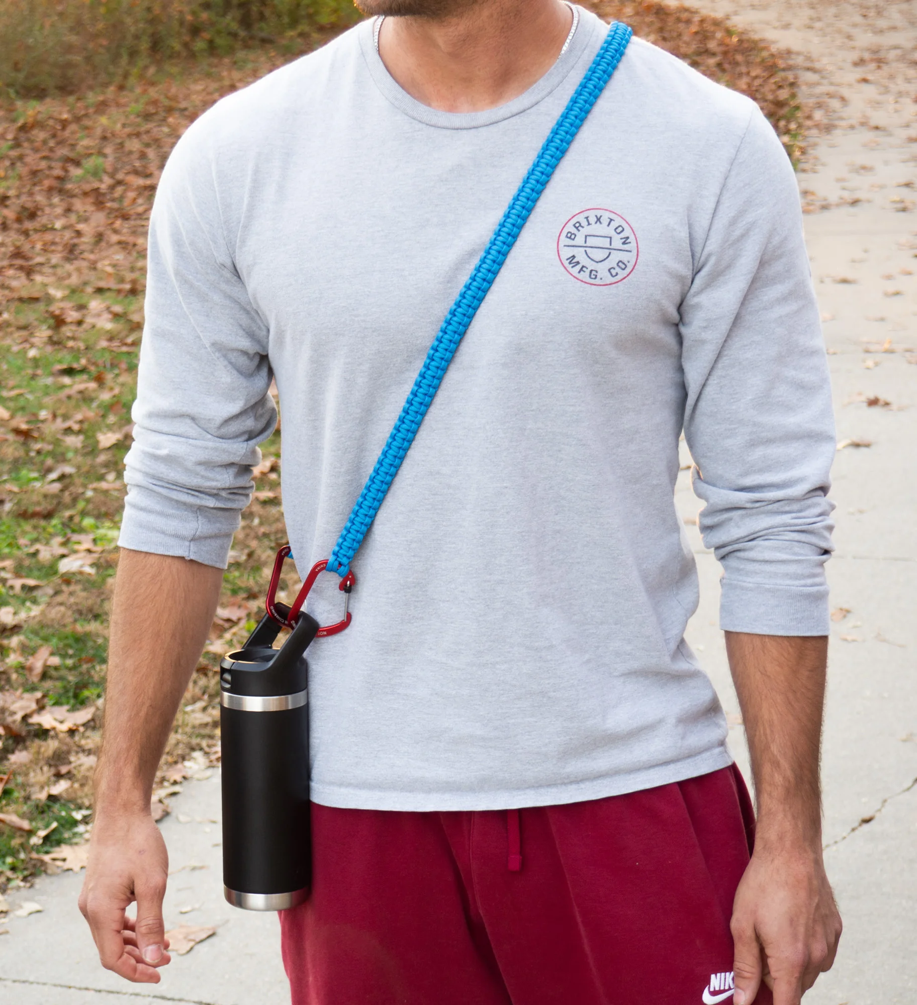 Blue custom-length THIRSTLOCK™ bottle sling worn cross-body on the torso.