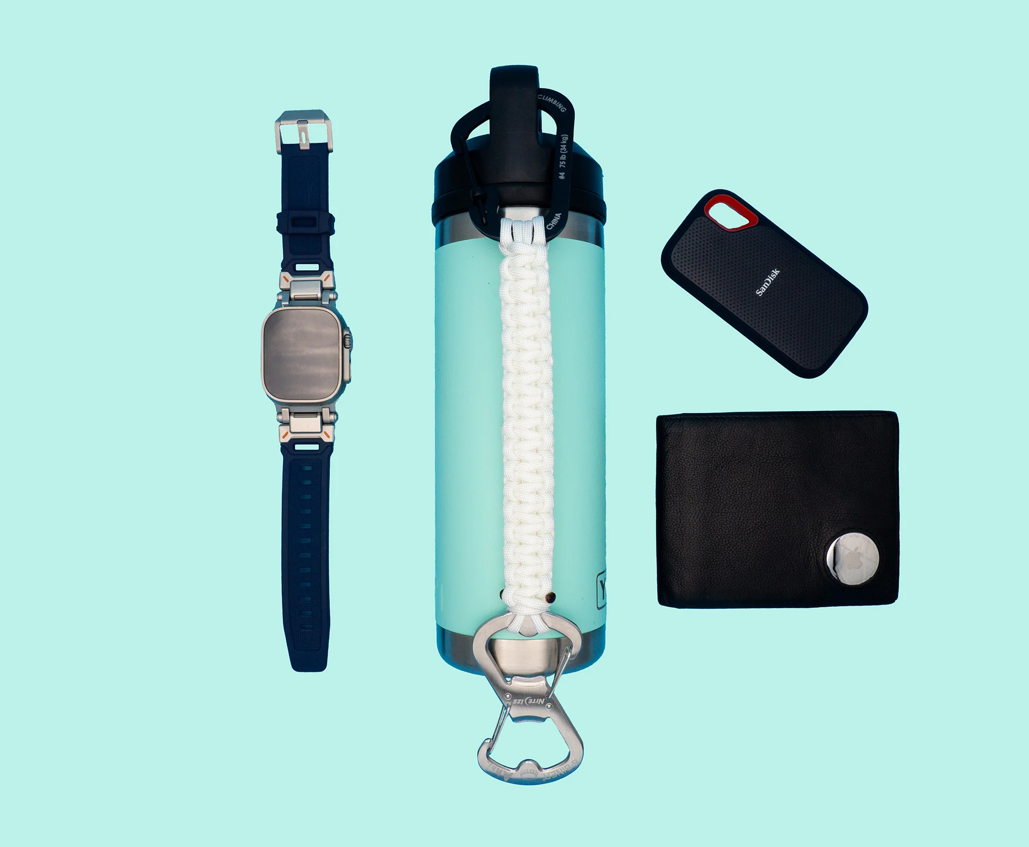 White THIRSTLOCK™ ANCHOR™ bottle leash attached to a water bottle and shown with everyday tech carry items including
             a smartwatch, wallet, and portable SSD.